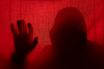 Wall Mural - Man silhouette behind a curtain in red light. Halloween and violence concept