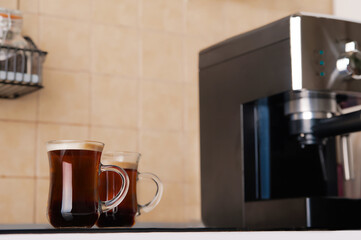 Two transparent cups coffee close-up front view. Home coffee maker and process of making coffee drink.