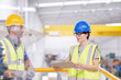 Supervisor and worker with clipboard talking in factory