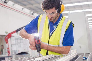 Wall Mural - Male engineer with power drill assembling equipment in steel factory