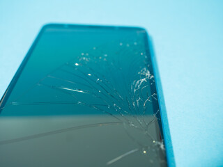 Wall Mural - Black crashed smartphone with broken screen and body on a blue table in service.