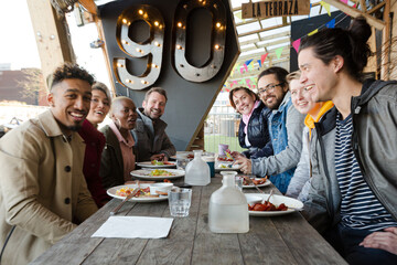 Portrait of smiling friends eating at restaurant outdoor patio