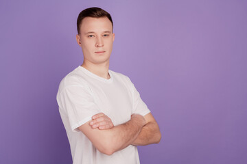 Wall Mural - Portrait of serious strong guy folded arms on violet background