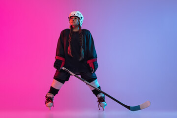 Wall Mural - Discipline. Portrait of child girl - professional hockey player isolated over gradient pink purple background.