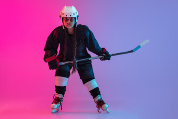 Wall Mural - Portrait of child girl - professional hockey player isolated over gradient pink purple background. Goal scoring