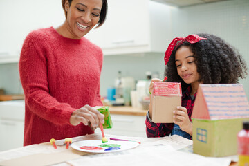 Mother and daughter painting cardboard houses