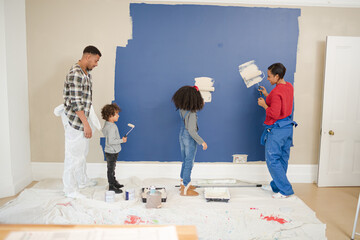 Wall Mural - Happy, playful family with paint rollers painting room