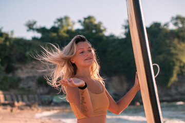 Wall Mural - Portrait of young blonde surfer girl with long surf board single fin on the beach at golden hour, sunset