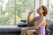 © SHUTTER DIN - housewife sitting on sofa and drinking mineral water in plastic bottles
