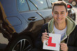 Portrait confident, happy young man holding learners permit by car