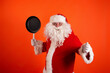 Funny fat Sanat Claus with a frying pan in his hands on an orange background. Copy space.