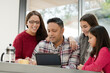 © KOTO - Happy family using digital tablet at kitchen table