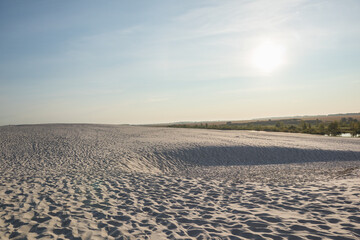 Snow white sand beach at sunrise and trees on the horizon