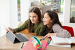 © KOTO - Sisters doing homework, sharing digital tablet at table
