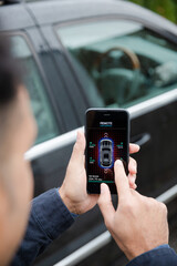 Wall Mural - Man setting car alarm from smart phone in driveway