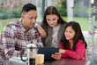© KOTO - Father and daughters using digital tablet in morning kitchen