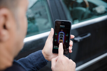 Wall Mural - Man setting car alarm from smart phone in driveway