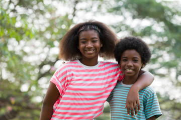 Wall Mural - Smiling African American boy and girl playing and hugging together outdoor. Happy afro kid having fun or enjoying together in the park. Happy black people. Education and field trips concept