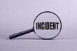 Magnifying glass with INCIDENT lettering on a gray background.