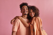 © Look! - Portrait of young, beautiful and swarthy couple lovers looking at camera with smiley face on pink background. Curly-haired brown-haired woman gently hugs partner in photo, dressed casual outfits.