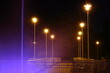 Fontanna podświetlona nocą z widokiem na latarnie.