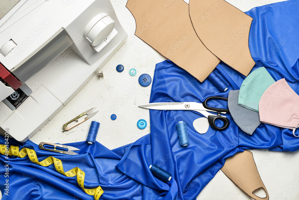 Sewing machine with tailor's supplies and protective masks on light background