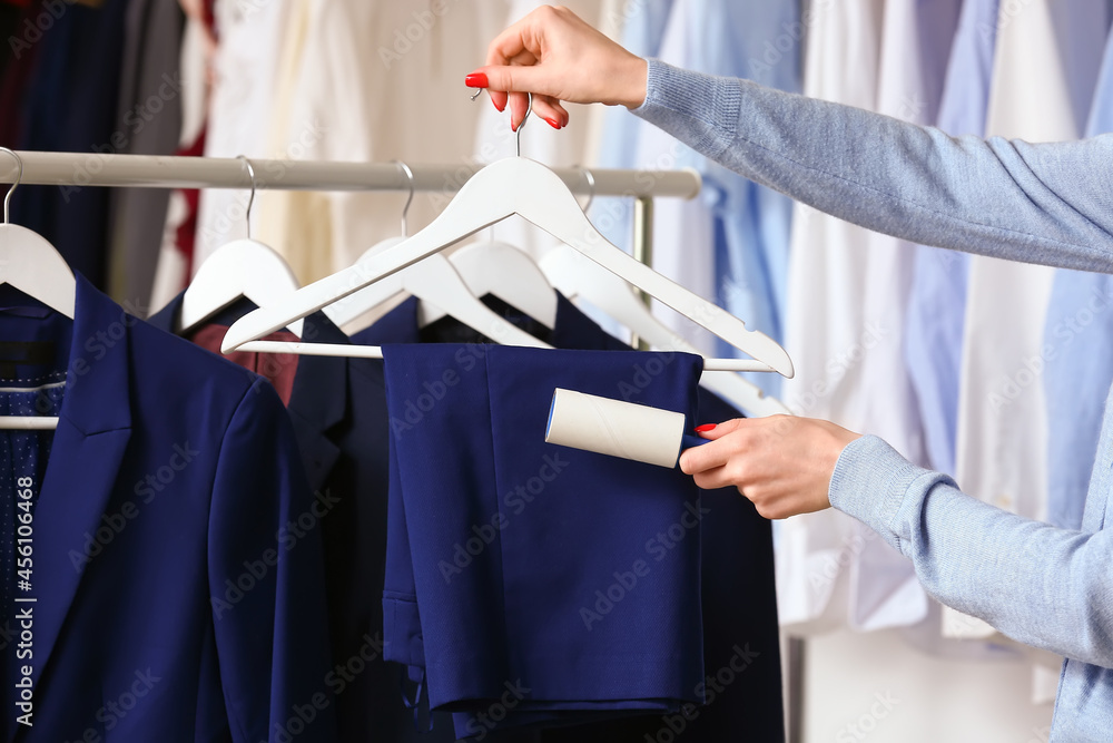 Woman cleaning clothes with lint roller in room