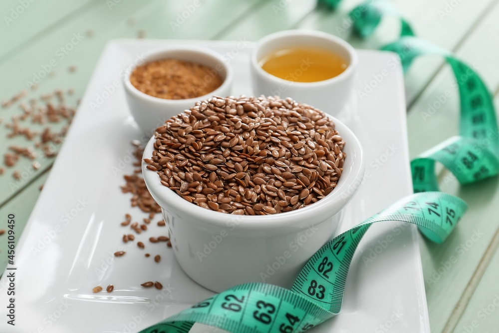 Bowl with flax seeds and measuring tape on table, closeup