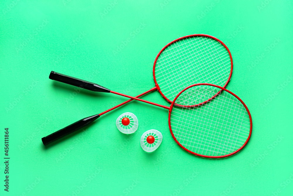 Badminton rackets and shuttlecocks on color background