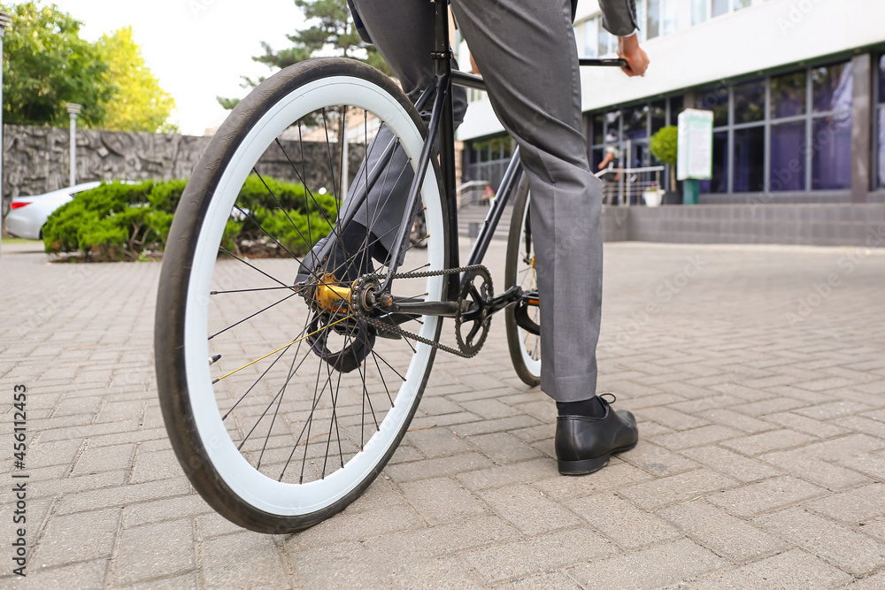 Businessman going to work by bicycle on city street