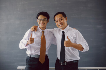 Two Asian businessman in white shirt and tie smiling while embrace together and giving thumb up to the camera