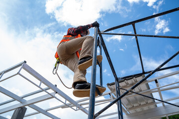 Worker wearing safety equipment and safety belts working on height at construction site.