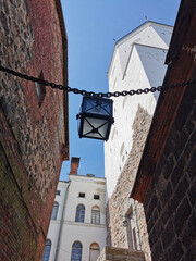 A narrow passage with a lantern suspended on chains, between the stone walls of the Vyborg Castle to the courtyard to the Tower of St. Olaf in the city of Vyborg