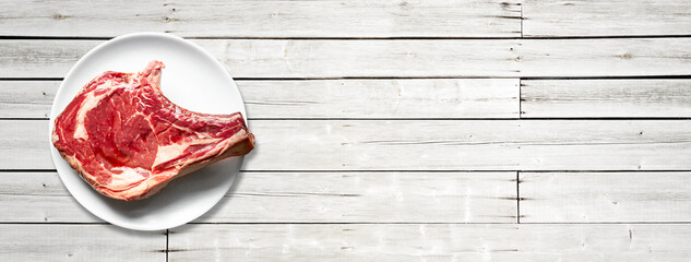 Wall Mural - Beef prime rib and plate isolated on white wooden background. Horizontal banner