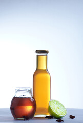 Sticker - Vertical shot of honey in a glass jar and bottle with anise stars, lime on white background