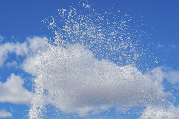 Canvas Print - Sea of splashes and stream of water from fountain soaring skyward against of blue cloudy summer sky.