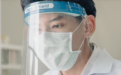 Health care worker wearing medical protective mask and face shield to prevent himself from virus infection while working in hospital laboratory. Basic safety equipment from flu spreading is face msk.