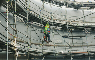 Construction workers tank oil installing scaffolding