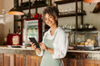 © (JLco) Julia Amaral - Smiling entrepreneur holding a digital tablet in her cafe