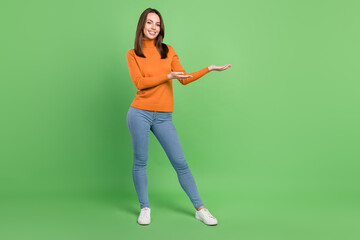 Poster - Full length body size photo girl in stylish outfit showing empty space on palm isolated pastel green color background