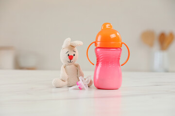 Wall Mural - Baby bottle, toy and pacifier on white marble table indoors. Maternity leave concept