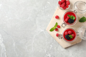 Delicious panna cotta with fruit coulis and fresh berries on light grey table, top view. Space for text