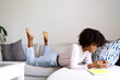 © sashapritchard - Young black woman with afro hair laying down on couch using her phone