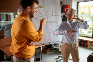 Wall Mural - A senior business woman has a conversation with her male colleague while holding a presentation at workplace. Business, office, job