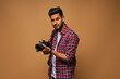 Young indian photographer with proffesional black camera on pastel background