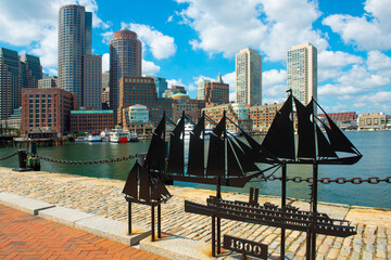 Antique ships sculpture with Boston Rowes Wharf and modern Financial District skyline at the background, city of Boston, Massachusetts MA, USA. 