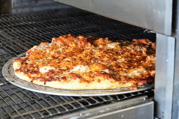 Wall Mural - Delicious pizza with lots of cheese and ingredients being cooked in the oven