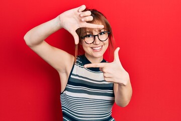 Sticker - Redhead young woman wearing casual clothes and glasses smiling making frame with hands and fingers with happy face. creativity and photography concept.