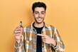 © Krakenimages.com - Young hispanic man holding electronic cigarette smiling happy pointing with hand and finger
