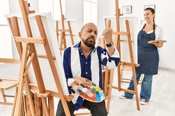 Canvas Print - Senior artist man at art studio angry and mad raising fist frustrated and furious while shouting with anger. rage and aggressive concept.